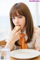 A woman sitting at a table eating a piece of food.