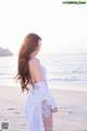 A woman standing on a beach next to the ocean.