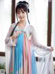 A woman in a blue and pink hanfu dress posing for a picture.