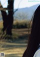 A woman with long black hair standing in a field.