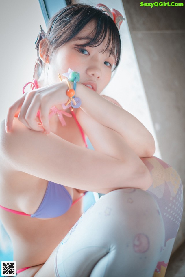 A woman in a bikini sitting on a window sill.