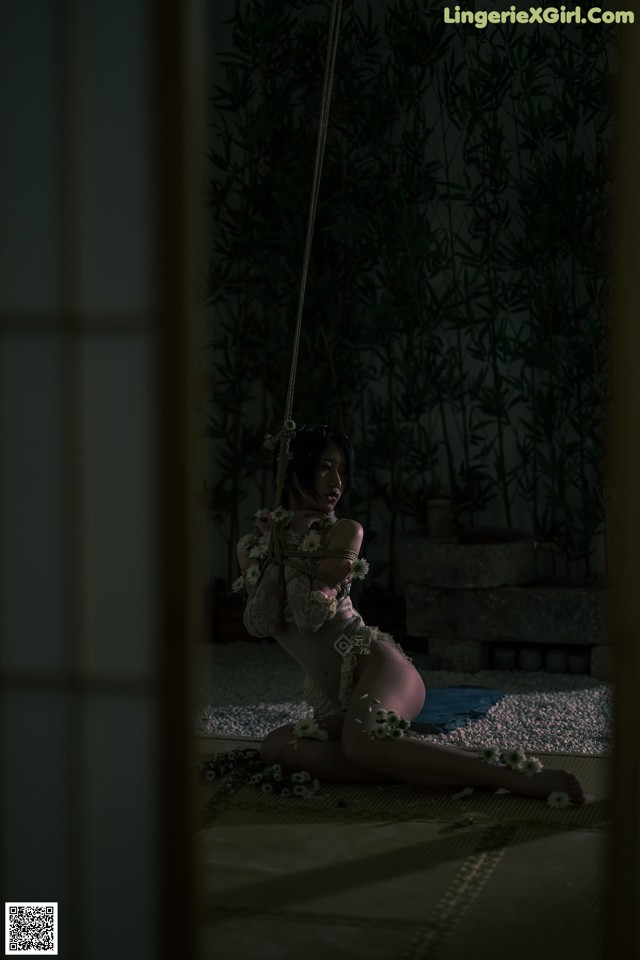 A woman sitting on a swing in a dark room.