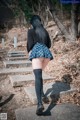 A woman in a skirt and stockings walking up some steps.