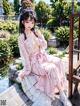 A woman in a pink kimono sitting on a wooden bench.