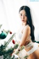 A woman in lingerie posing next to a Christmas tree.