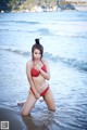 A woman in a red bikini standing in the water.