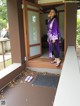 A woman in a purple kimono standing on the porch of a house.