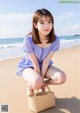 A woman sitting on a beach holding a basket.