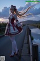 A woman in a red and white dress standing on a bridge.