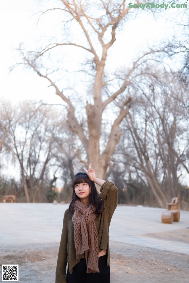A woman standing in front of a large tree.