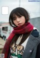 A woman wearing a red scarf standing in front of a building.