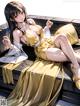 A woman in a yellow dress sitting on a wooden bench.