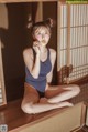 A woman in a blue swimsuit sitting on a wooden platform.