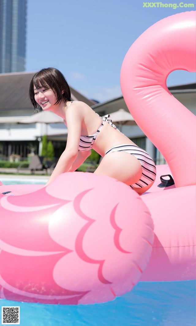 A woman in a bikini sitting on an inflatable flamingo in a pool.