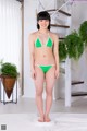 A woman in a green bikini standing on a scale.