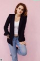 A woman in a black blazer and jeans posing for a picture.