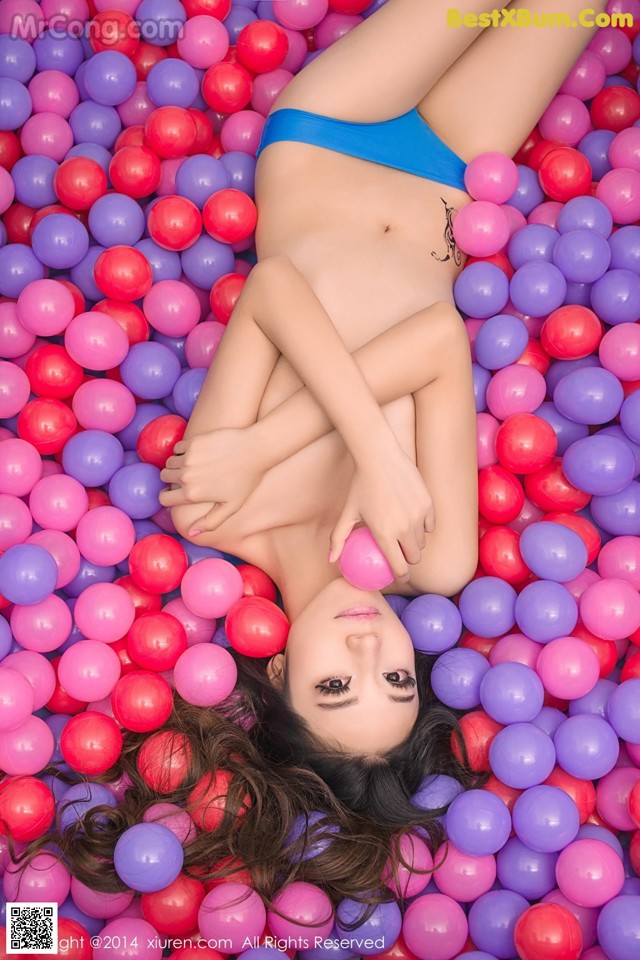 A woman in a blue bikini laying in a ball pit.